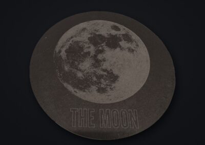 Runde Schieferplatte mit gravierter Mondabbildung und dem Schriftzug THE MOON